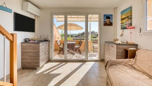Una habitación moderna con puerta de vidrio corrediza a un balcón, una televisión de pantalla plana, una mesa de comedor de madera y una cama.