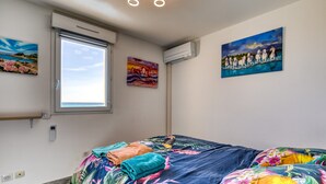 Un dormitorio con una cama, una ventana y dos cuadros colgados en la pared.