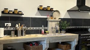 A modern kitchen with a central island, black stove, and a range hood.