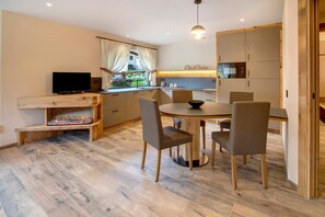 Una cocina moderna con comedor, suelo de madera y televisor.