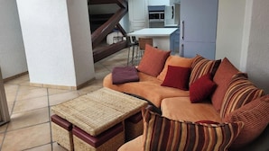 Ein Wohnzimmer mit einer Couch, einem kleinen Tisch und einer Treppe, die zu einer oberen Ebene führt.