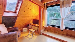 A cozy room with wooden walls, a wooden bench, a small stool, and a window with curtains. - Chalet BomBom - Cozy cocoon with pond view in Mittlach (Mittlach)