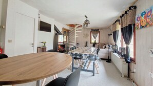 A cozy living room with a fireplace, a dining table, and a sofa.