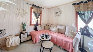 A cozy room with a sofa, a small round table, a potted plant, and a decorative mirror on the wall.