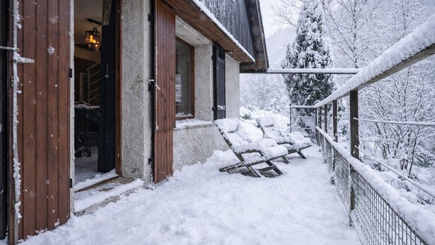 A snow-covered outdoor area with a wooden deck and a metal railing.