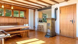 A wooden dining table with chairs, a kitchen area with a stove, and a large wooden door. - Stay in the heart of the Gaschney 360° resort (Muhlbach-sur-Munster)
