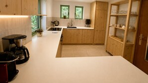 A modern kitchen with wooden cabinets, a white countertop, and a built-in glass display cabinet. - Stay in the heart of the Gaschney 360° resort (Muhlbach-sur-Munster)