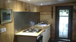 A compact kitchen with wooden walls, a gas stove, and a sink. - In the midst of wildlife and marshland, a ton of thrills and chills  (Vendays-Montalivet)