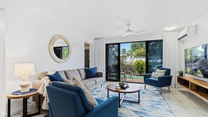 A modern living room with a sofa, armchairs, a coffee table, and a TV.