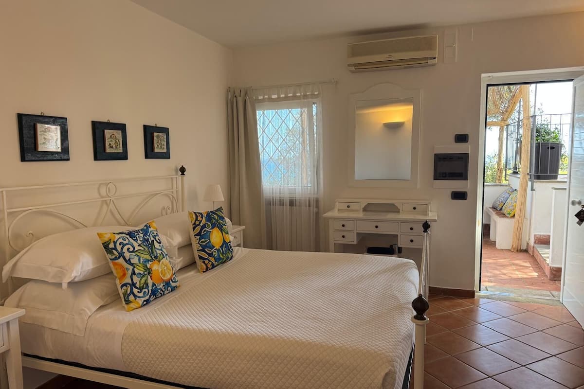Un dormitorio con cama, cómoda, espejo y ventana con cortinas.