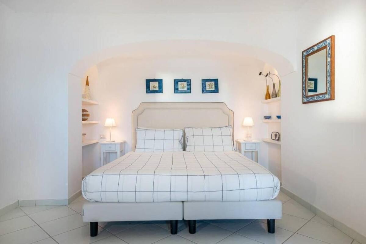 Un dormitorio con una cama, dos mesitas de noche y tres cuadros enmarcados en la pared.