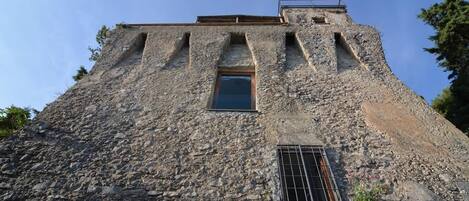 A stone building with a window and a metal grate at the bottom.