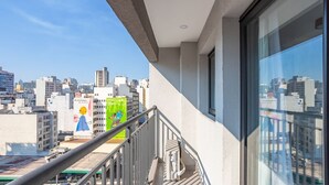 A cityscape view from a balcony with a clear sky, featuring modern buildings and a visible power box. - ISC - Well-located Studios in Vila Buarque, Sao Paulo (São Paulo)