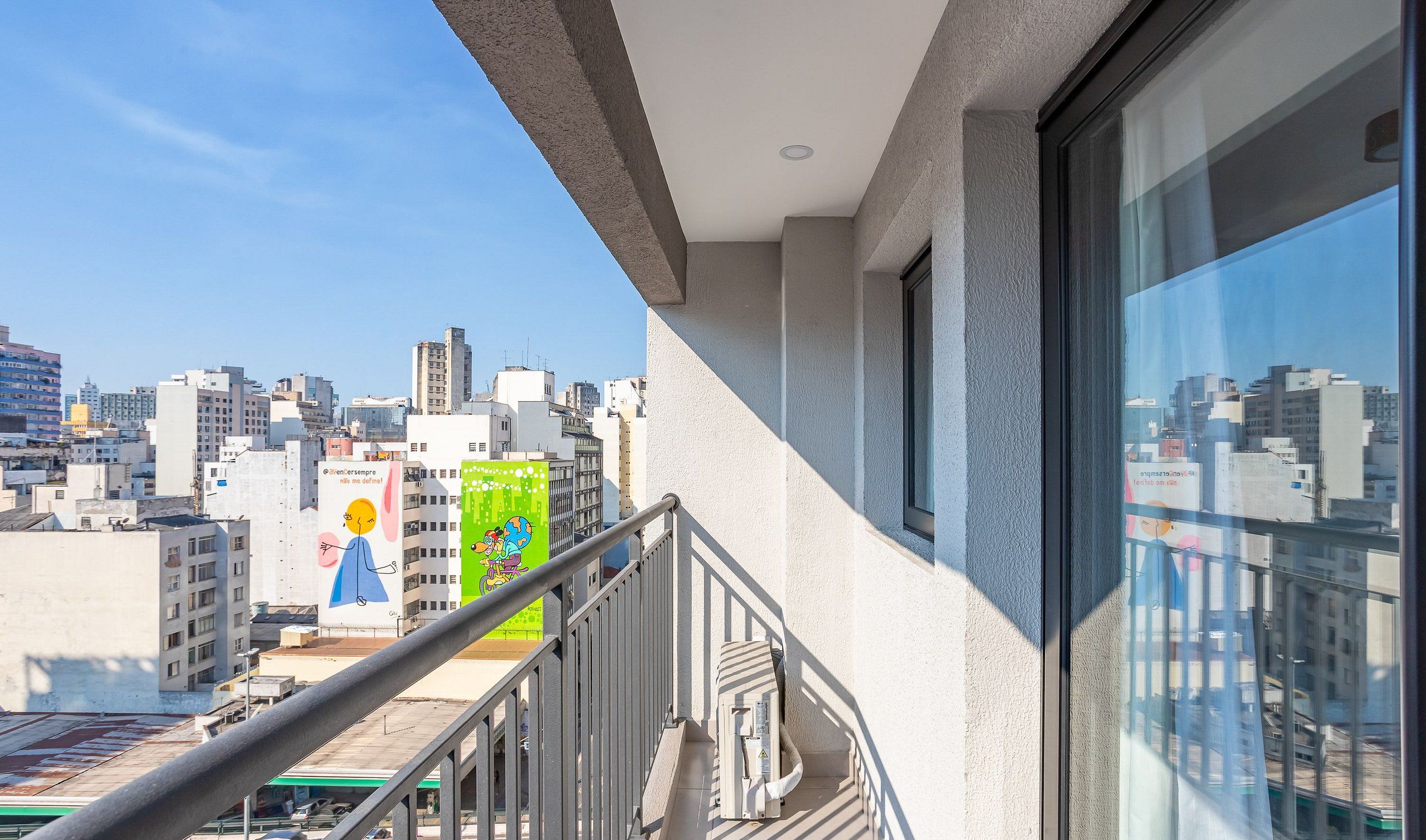 Udsigt over bybilledet fra en balkon med klar himmel, der viser moderne bygninger og et synligt eltårn.