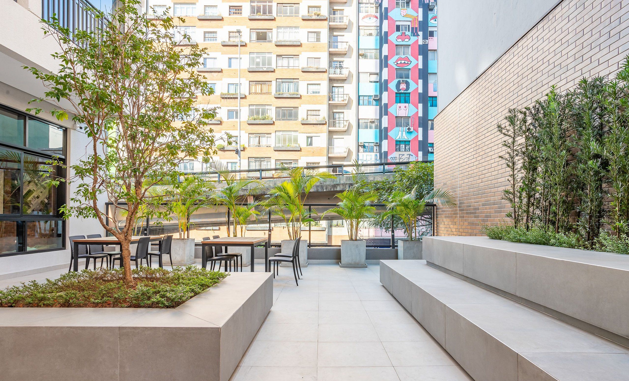 An outdoor patio area with seating and planters, surrounded by buildings.