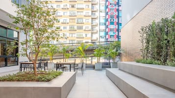 An outdoor patio area with seating and planters, surrounded by buildings.
