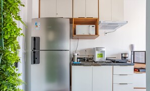 Eine moderne Küche mit einem Edelstahl-Kühlschrank, einer Mikrowelle und einer Kaffeemaschine.