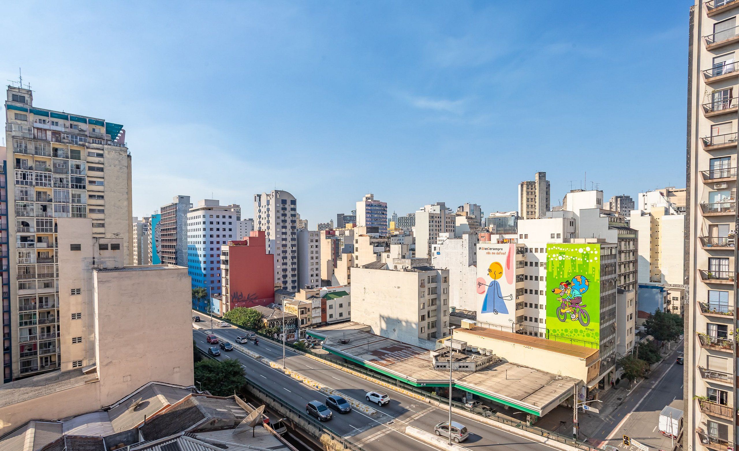 Un paysage urbain avec de hauts immeubles, une autoroute et un panneau publicitaire.