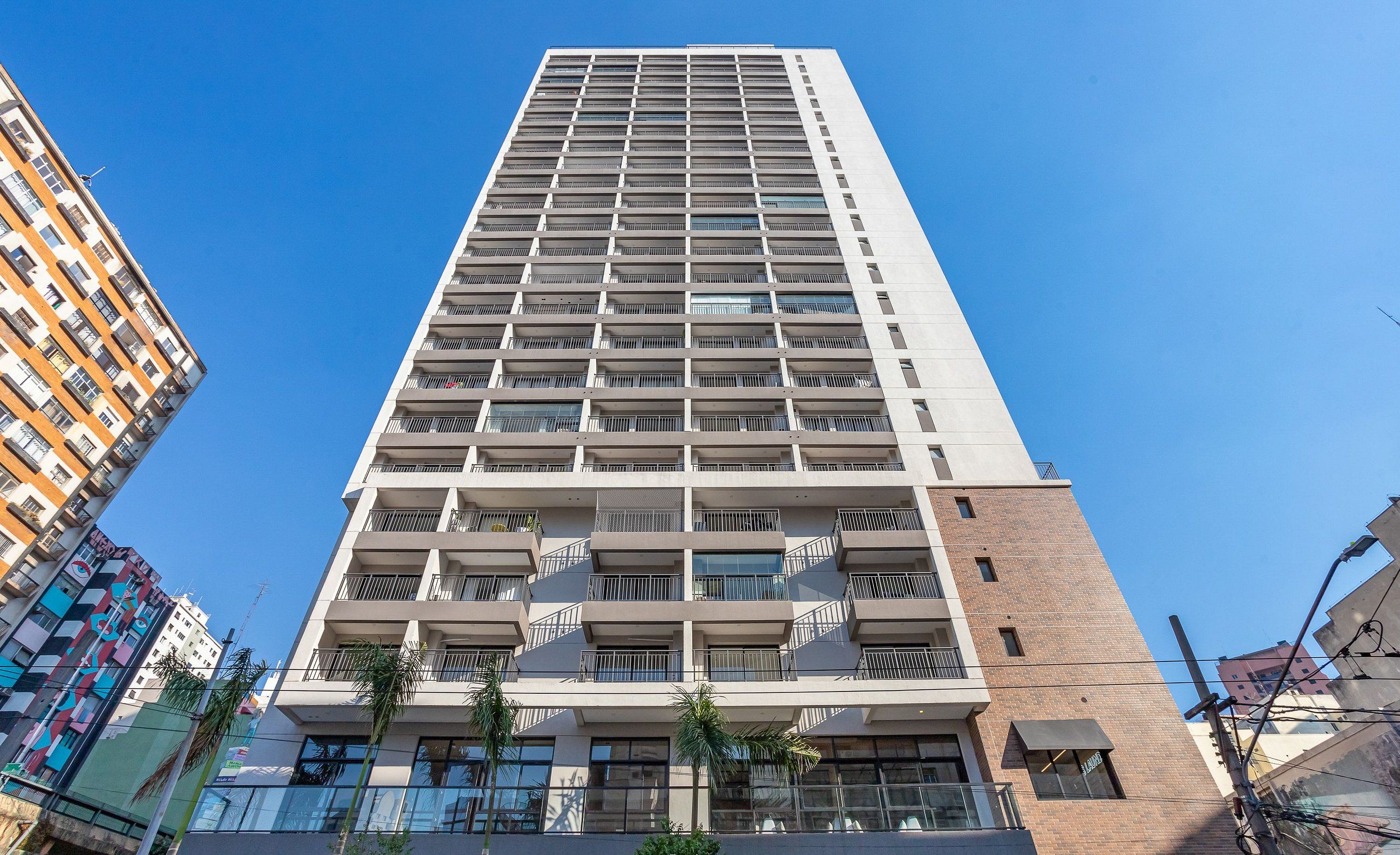 Um edifício alto e moderno com várias varandas e uma placa com a inscrição 'seazone'.