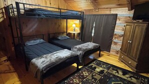 Uma cabana com duas beliches, um ventilador de teto, um tapete e um armário.