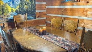 Uma sala de jantar de madeira com uma mesa grande, cadeiras e um lustre.