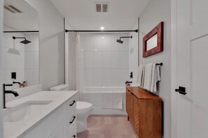 Une salle de bain moderne avec un lavabo, des toilettes et une zone de douche, le tout de couleur blanche.