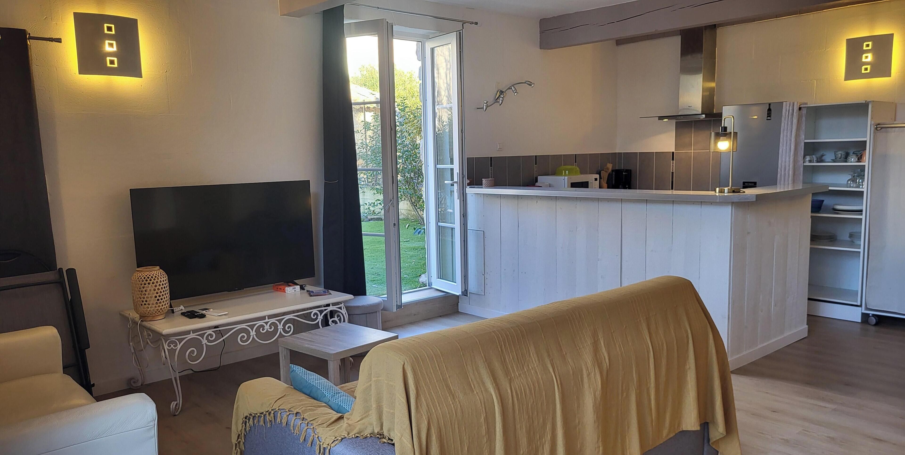 Una sala de estar moderna con televisor, asientos y una zona de cocina con barra.