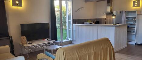 Una sala de estar moderna con televisor, asientos y una zona de cocina con barra.