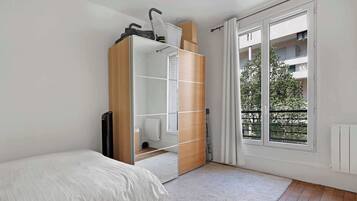 Une chambre à coucher comprenant un lit, une armoire, un miroir et une fenêtre donnant sur un balcon.