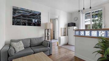 Un salon moderne avec un canapé gris, une table basse en bois et un grand tableau encadré accroché au mur.