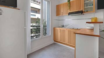 Une cuisine moderne avec des meubles en bois, un four encastré et une grande fenêtre donnant sur le balcon.