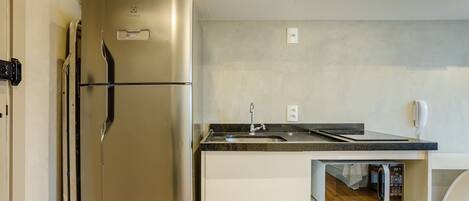 Una cocina compacta con un refrigerador de acero inoxidable, un microondas y un lavamanos.