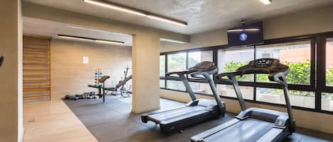 A modern gym with treadmills, weight machines, and a large window providing natural light.