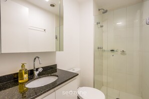 A modern bathroom with a glass-enclosed shower, a white toilet, and a granite countertop with a soap dispenser. - Modern Studio 450m From the Subway Ism0806 (São Paulo)
