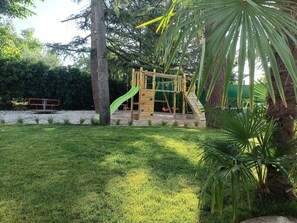 Ein Spielplatz mit Rutsche, Kletterwand und Schaukeln.