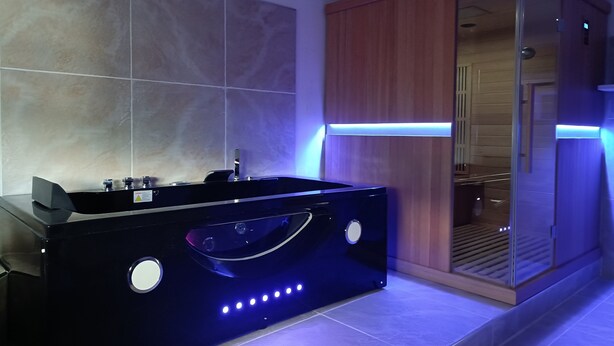 Un baño moderno con una bañera negra, un armario de madera y una cabina de ducha de vidrio.