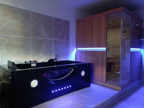 Une salle de bain moderne avec une baignoire noire, un meuble en bois et une cabine de douche en verre.