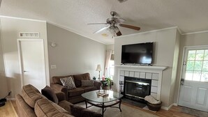 A living room with a sofa set, a coffee table, a fireplace, and a ceiling fan.