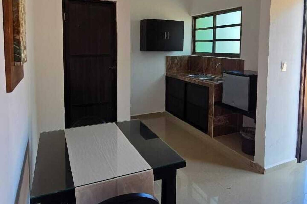 A compact living space with a dining area, kitchenette, and a ceiling fan.