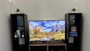 Un téléviseur à écran plat posé sur un meuble télé en bois, avec deux étagères noires de chaque côté.