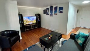 Un salon équipé d’un téléviseur à écran plat, d’un canapé en cuir noir et d’une table basse.
