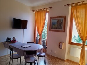Ein Essbereich mit Tisch, Stühlen, einem Fernseher und einem Bild an der Wand.