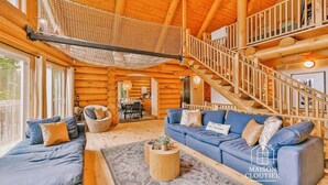 A log cabin interior with a living room, dining area, and staircase.