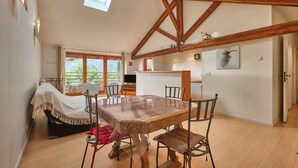 A spacious room with a wooden dining table, chairs, a bed with a white canopy, and a skylight. - Holiday Home 'Maison' with Mountain View and Wi-Fi (Noyarey)