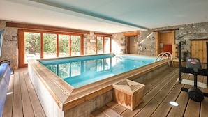 A swimming pool with wooden deck, stone walls, and large windows. - Holiday Home 'Maison' with Mountain View and Wi-Fi (Noyarey)
