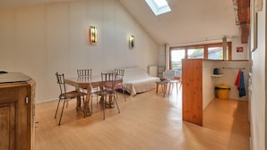 A loft-style room with a dining area, a bed, skylights, and a small kitchen area. - Holiday Home 'Maison' with Mountain View and Wi-Fi (Noyarey)