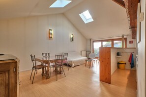 Una stanza in stile loft con zona pranzo, letto, lucernari e angolo cottura.