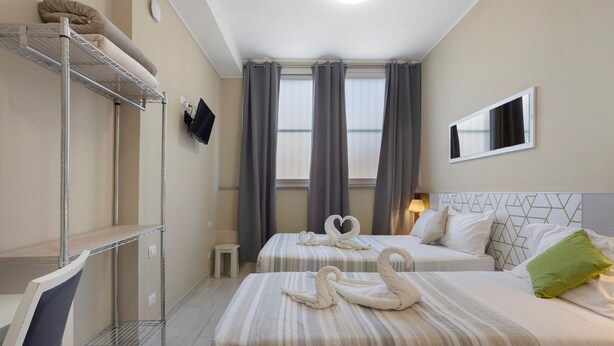 A hotel room with two beds, a desk, a TV, and a window with curtains. - Room 'Tripla' with Wi-Fi and Air Conditioning (Milano)