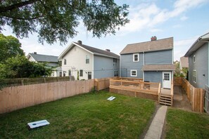 A residential backyard with a wooden fence, a small wooden deck, and a grassy lawn.