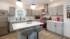 Una cocina moderna con una isla central, electrodomésticos de acero inoxidable e iluminación colgante.